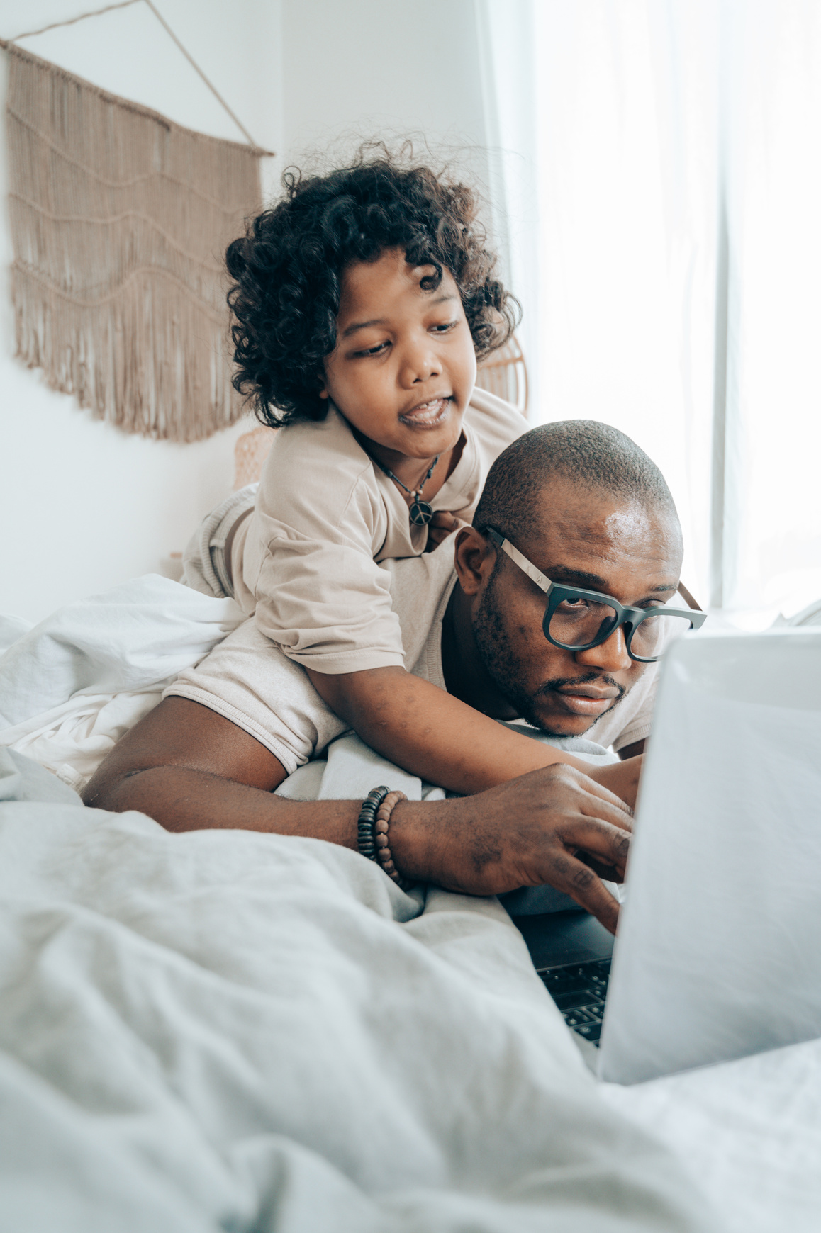 Parent and kid with laptop in bedroom